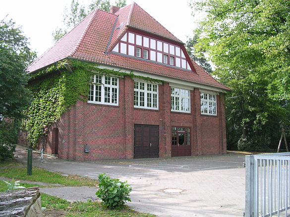 Fotografie des roten Backsteingebäudes, Baujahr 1911, mit umgebendem Schulhof